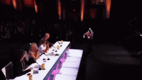 a group of people are sitting at a table with a pink sign that says xxx on it .