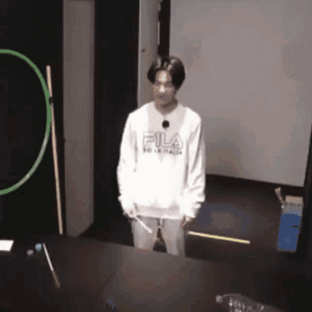 a man wearing a fila sweatshirt is standing in front of a table holding a hula hoop .