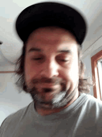 a man with a beard is wearing a hat and making a face