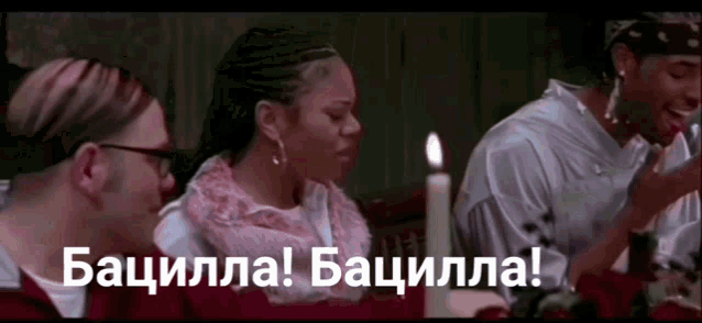 a group of people are sitting around a table with a candle and the words bacilla bacilla written on the bottom