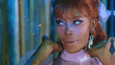 a woman with red hair is wearing a white dress and earrings .