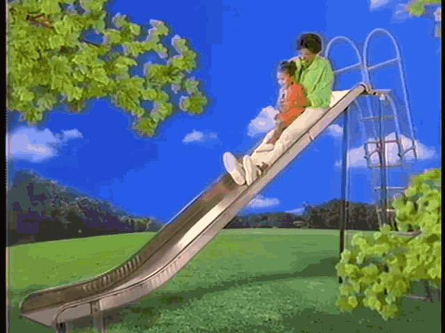 a woman and child are riding down a metal slide