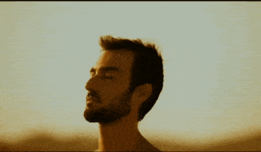a shirtless man with his eyes closed looks at the camera