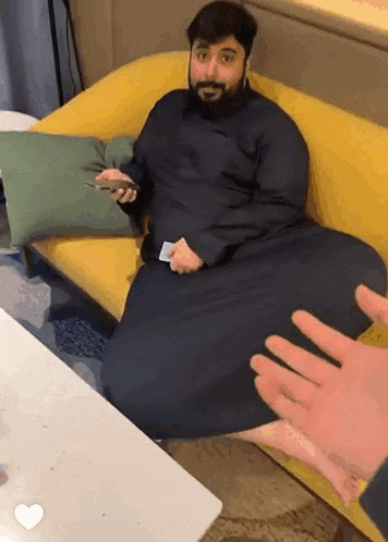 a man sitting on a yellow couch holding a card