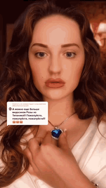 a woman wearing a necklace with a heart shaped pendant