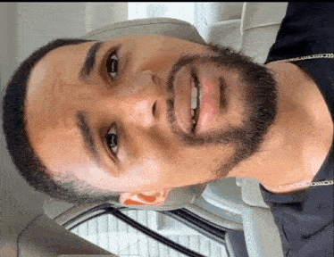 a close up of a man 's face with a beard and a chain around his neck