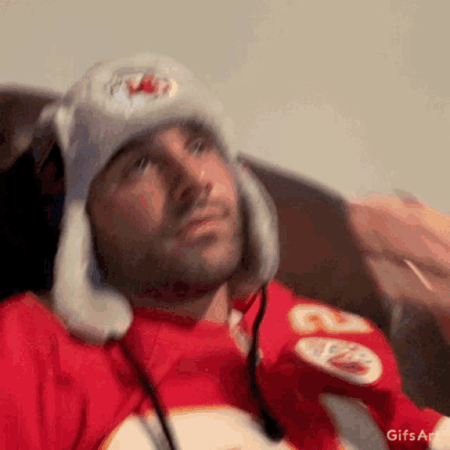 a man wearing a kansas city chiefs jersey and a hat