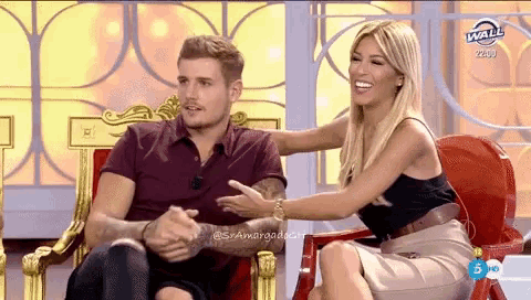 a man and a woman are sitting next to each other and the woman is holding the man 's hand
