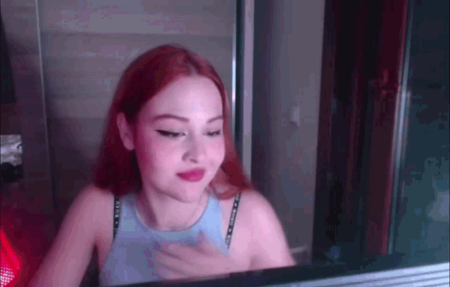 a girl with red hair is looking at herself in a mirror .