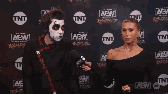 a man and a woman are standing in front of a wall that says aew