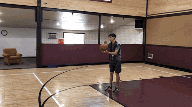 a man is holding a basketball in a gymnasium
