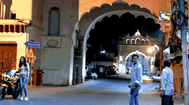 a man and a woman are walking down a street in front of a building that says sony