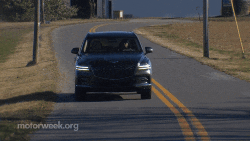 a car is driving down a road with motorweek.org written on the side