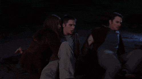 a man and two women are sitting on the ground in the dark