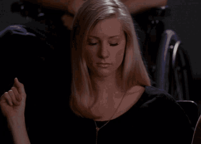 a woman in a black shirt is sitting in a chair with a man in a wheelchair behind her