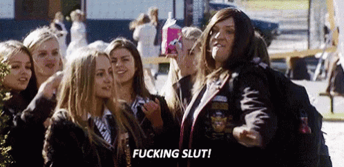 a group of young women are standing next to each other and a woman is smoking a cigarette .