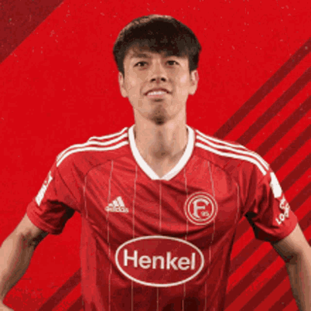a soccer player wearing a henkel jersey is smiling