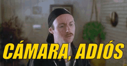 a man with a bandana on his head says camara adios in yellow letters