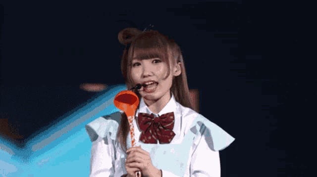 a girl in a school uniform is holding a spoon in her mouth