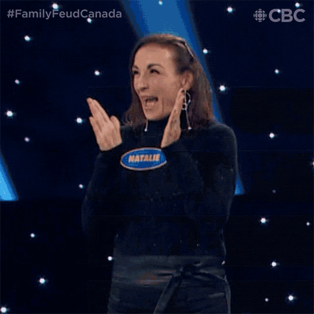 a woman is clapping her hands on a stage while making a funny face .