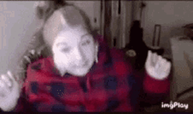 a girl in a plaid jacket is making a funny face while wearing headphones .