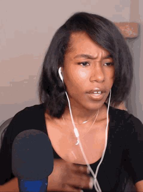 a woman wearing headphones and a black shirt looks angry