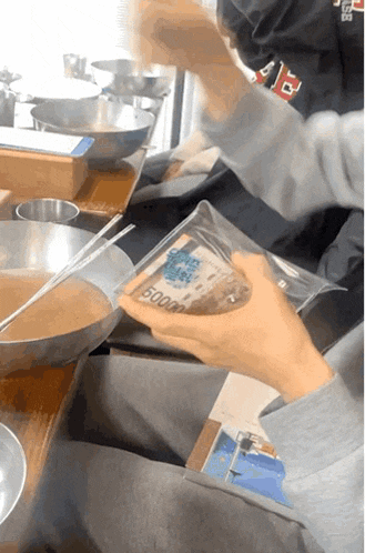 a person is holding a plastic container with a 5000 bill inside of it