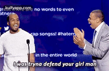 two men are standing next to each other in front of a microphone and one of them is laughing .