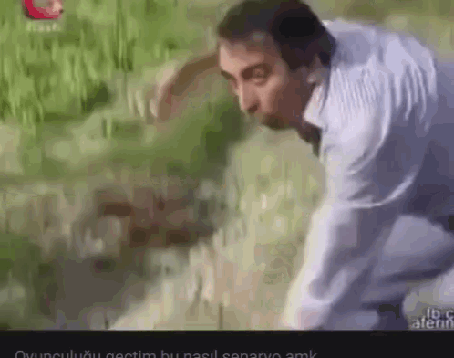 a man in a white shirt is standing in a grassy field .