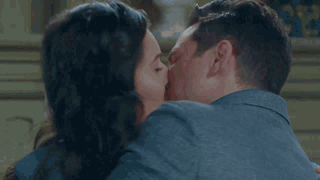 a man and a woman are kissing in front of a sign that says ' nbc ' on it