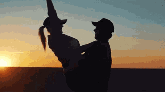 a man is holding a woman in his arms at sunset in the desert .