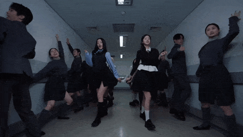 a group of people are dancing in a hallway with their hands up