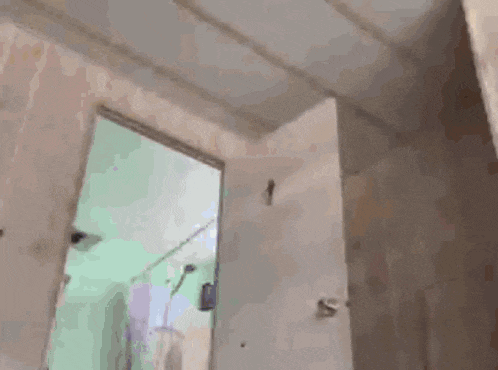 a bathroom with a green shower curtain and a white door open .