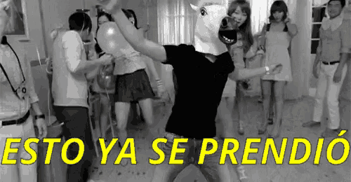 a man in a horse mask is dancing in front of a group of people with the words esto ya se prendio written in yellow