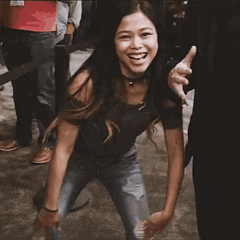 a woman is dancing in front of a crowd of people and smiling at the camera .