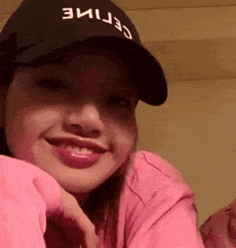 a woman wearing a celine hat and a pink shirt