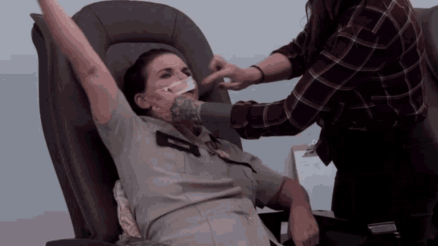 a woman with a tattoo on her arm is sitting in a chair with her arms up