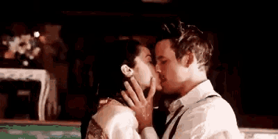 a man and woman are kissing each other in a dark room .