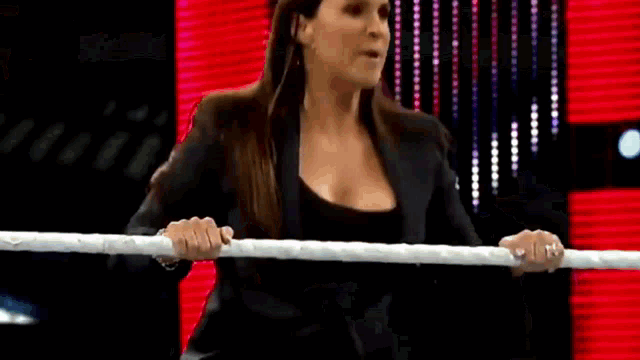 a woman in a black jacket is standing in front of a red light .