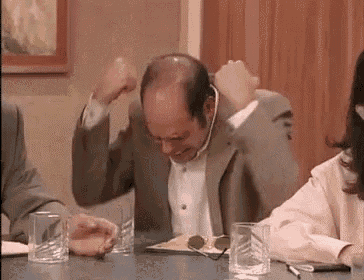 a man in a suit is sitting at a table with glasses of water and a woman in a pink shirt .