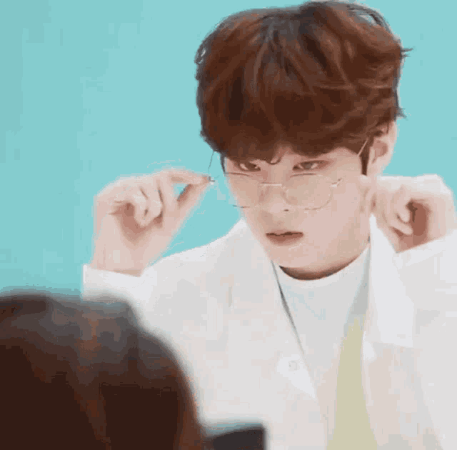 a young man wearing glasses and a white lab coat is looking at a woman .