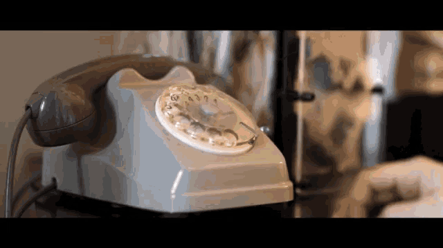 a person is talking on an old fashioned telephone that has a white dial