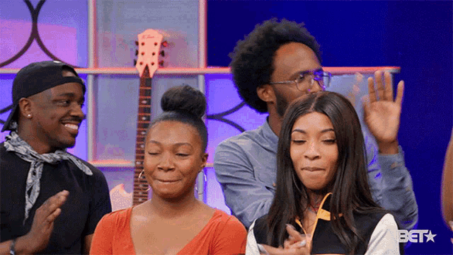 a group of people are clapping in front of a guitar and a bet logo