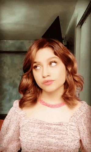 a woman with red hair and a pink necklace