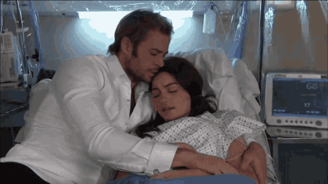 a man and a woman are laying in a hospital bed with a monitor that says 17