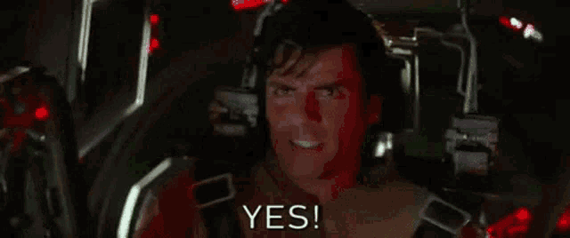 a man is screaming in a green room with the words `` yes '' written above him .