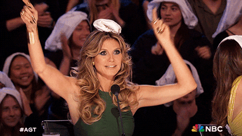 a woman in a green dress is giving a thumbs up in front of a crowd with nbc written on the bottom right