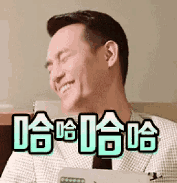 a man is smiling and sitting on a couch with chinese writing on the bottom of his face .