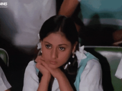 a girl sits with her head resting on her hands in front of a screen that says mines entertainment