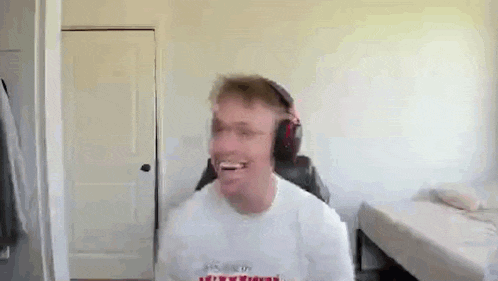 a man wearing headphones is smiling while sitting in a chair in a bedroom .